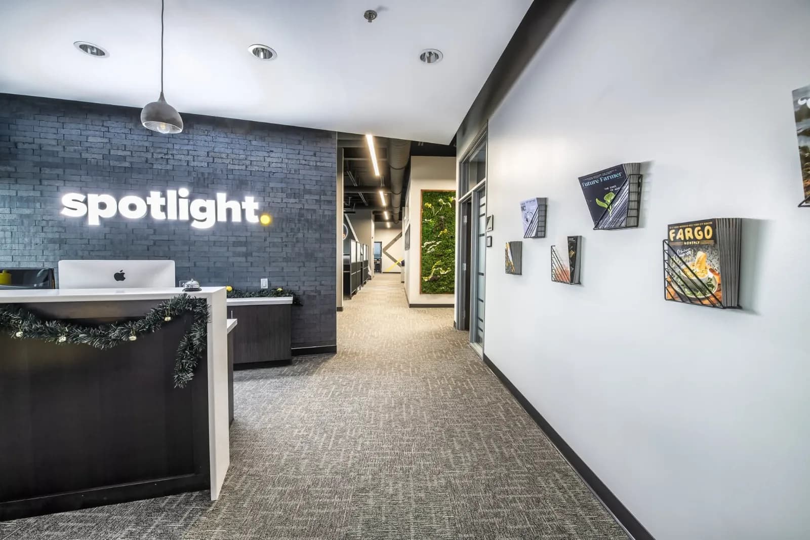 Spotlight Media reception desk with the lit spotlight wordmark and magazine racks