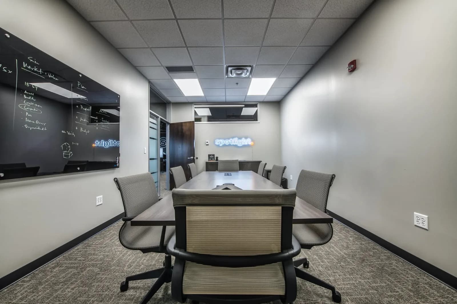 Spotlight Media conference room with a glass whiteboard and the neon spotlight sign